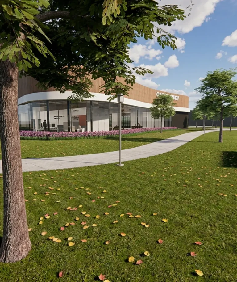Een modern gebouw met grote glazen ramen en een bloembed, omgeven door een groen grasveld en bomen.